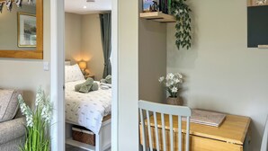 Ein gemütliches Zimmer mit einem Bett, einem Schreibtisch, einem Stuhl, einer Zimmerpflanze und einem Bücherregal.