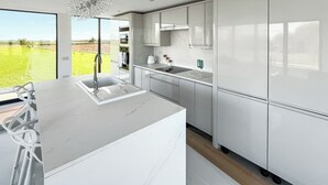 Eine moderne Küche mit einer großen Kochinsel, Edelstahlgeräten und Blick auf ein grünes Feld.