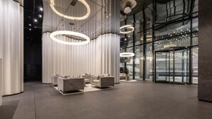 Una hall moderna con area salotto, ampie finestre e lampade circolari.