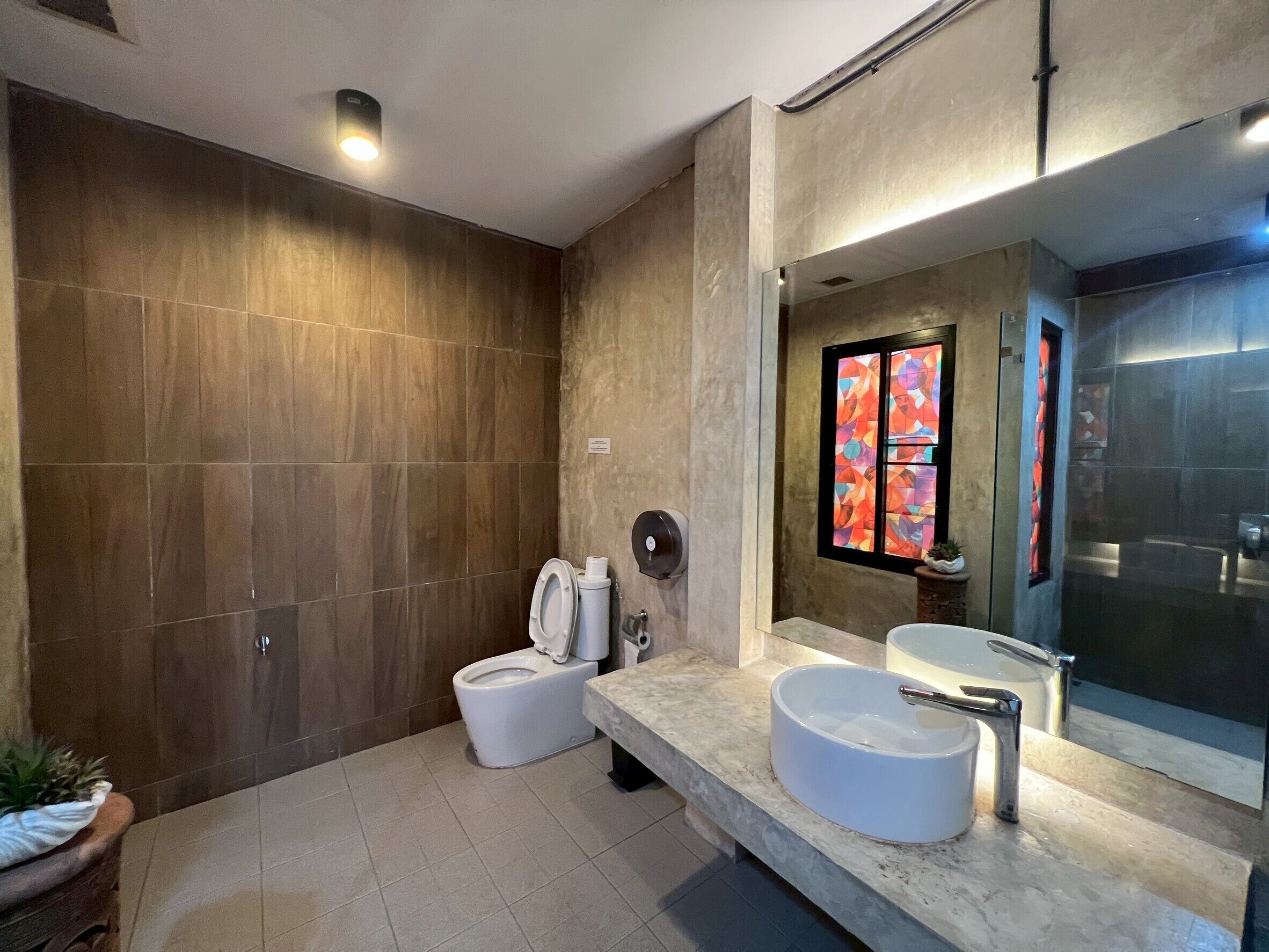 A modern bathroom with a large mirror, a toilet, a sink, and a shower area.