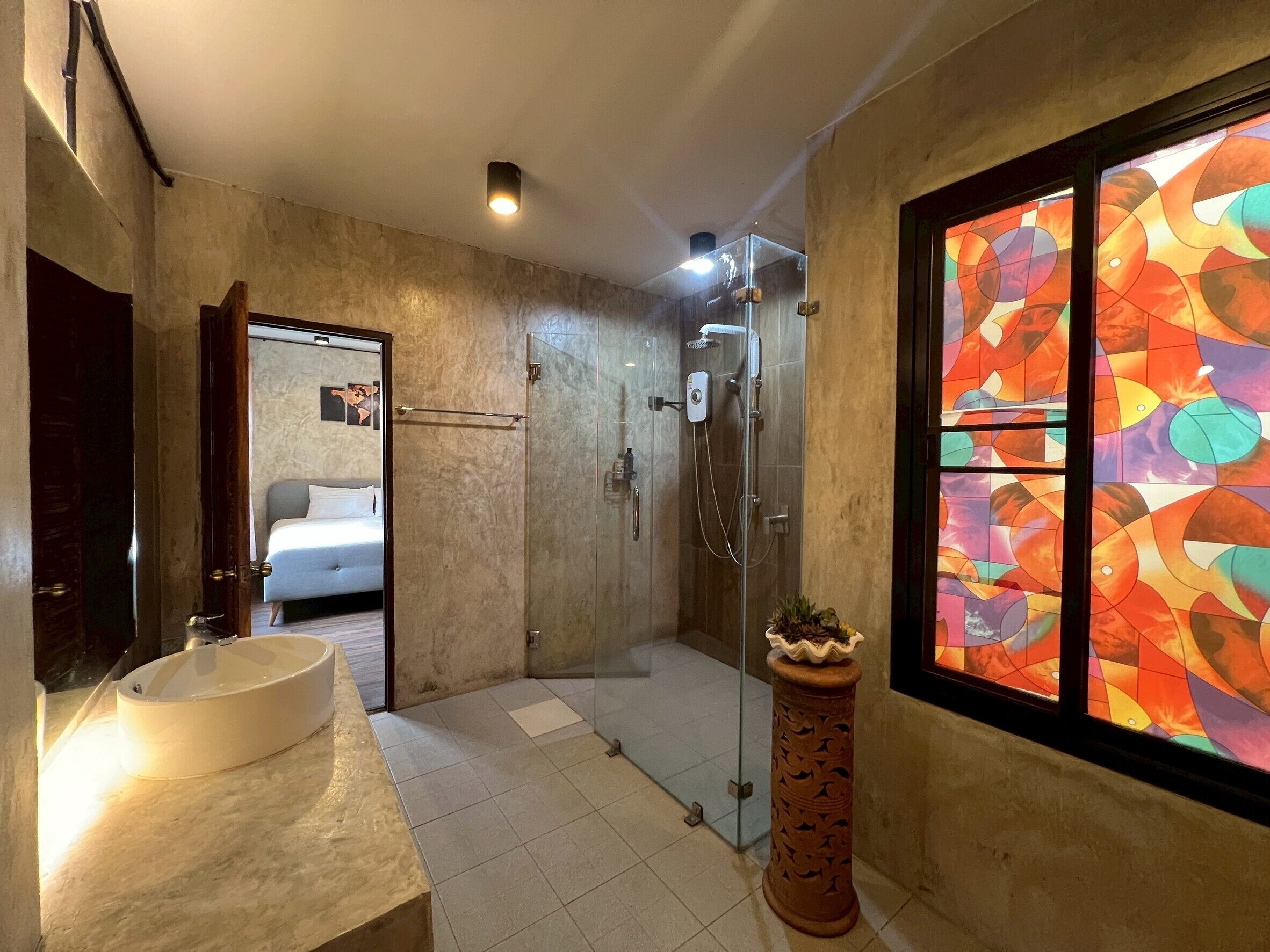 A bathroom with a glass-enclosed shower, a large mirror, and a sink.
