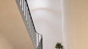 A staircase with a wooden handrail, a black metal railing, and two potted plants on the landing. - House 5 pers air-conditioned near Avignon/St Remy de Provence air-conditioned parking (Châteaurenard)