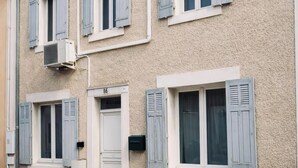 A two-story building with a stone facade, multiple windows with shutters, and a white door. - House 5 pers air-conditioned near Avignon/St Remy de Provence air-conditioned parking (Châteaurenard)