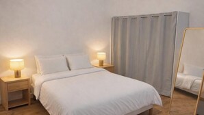 A bedroom with a wooden floor, a bed with white bedding, two bedside tables with lamps, and a large mirror. - House 5 pers air-conditioned near Avignon/St Remy de Provence air-conditioned parking (Châteaurenard)