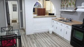 A modern kitchen with white cabinetry, a wooden countertop, and a black stove.