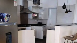Ett modernt kök med vita skåp, en svart bänkskiva och en inbyggd mikrovågsugn.