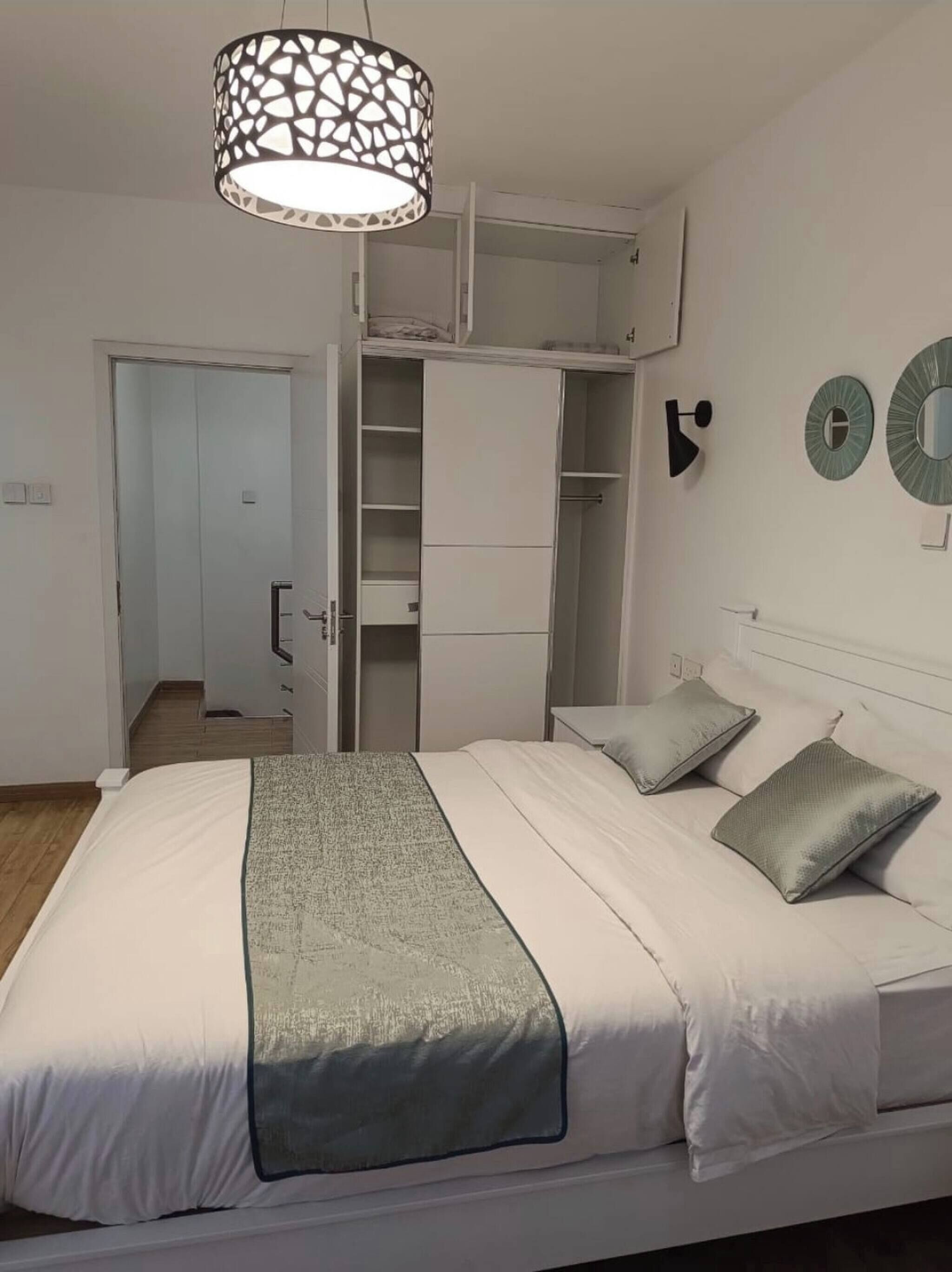 Ein Schlafzimmer mit Bett, Kleiderschrank, Pendelleuchte und Tür.