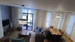 Ett modernt vardagsrum med en soffa, ett soffbord, ett matbord och en TV.