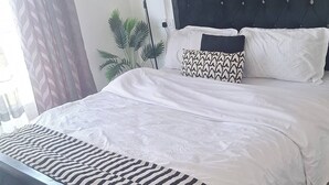 En snyggt bäddad säng med ett randigt överkast, en mörk sänggavel och en mönstrad matta på golvet.