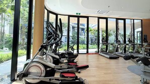 A gym with treadmills, stationary bikes, and weight machines, large windows, and a curved ceiling. - Dcondo Reef  kathu Patong (Kathu)