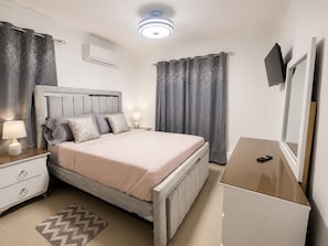 Een slaapkamer met een bed, nachtkastjes, een lamp, een spiegel en een dressoir.