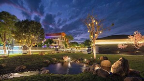 Un jardin aménagé avec un bassin, des arbres et un bâtiment au design moderne.