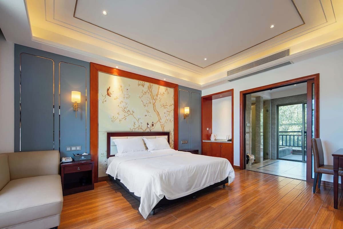 Une chambre d’hôtel avec un lit, une table de chevet, une chaise et une vue à travers une porte vitrée.