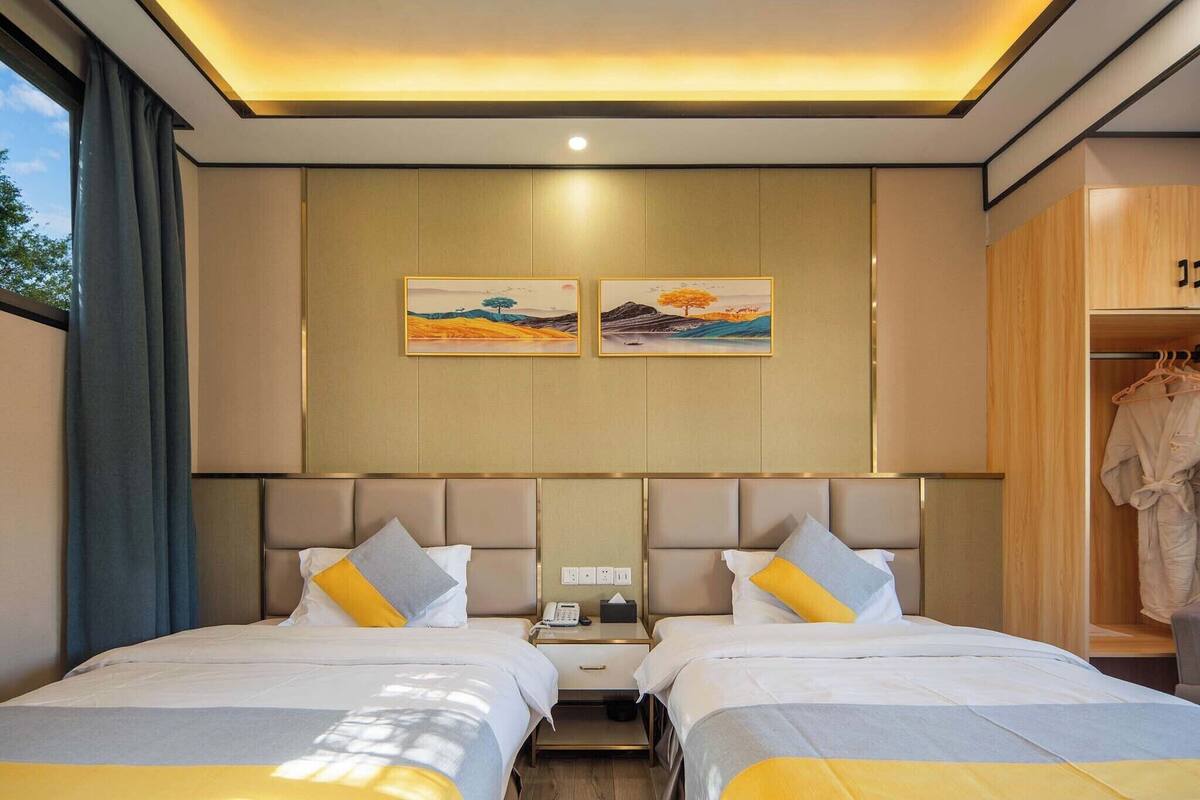 Une chambre d’hôtel avec deux lits, une table de chevet avec un téléphone et des mouchoirs, et une armoire avec des cintres.