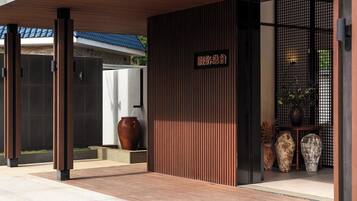 A modern building entrance with a wooden overhang, a signboard, and decorative vases.