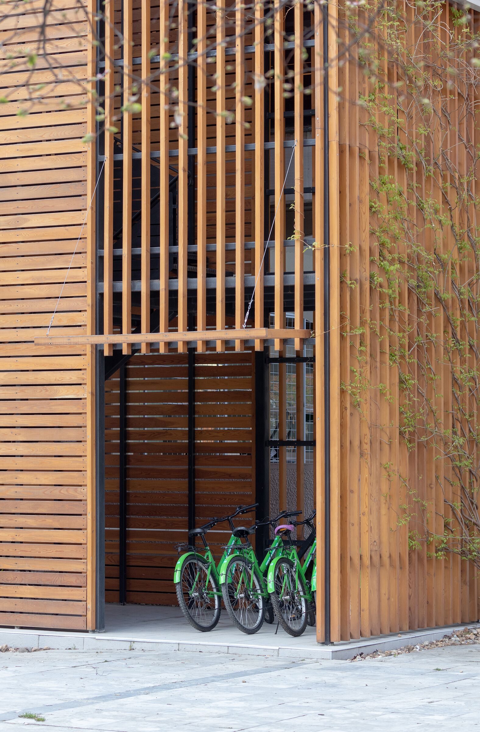 A modern building with a wooden facade, a large garage door, and two bicycles parked outside.