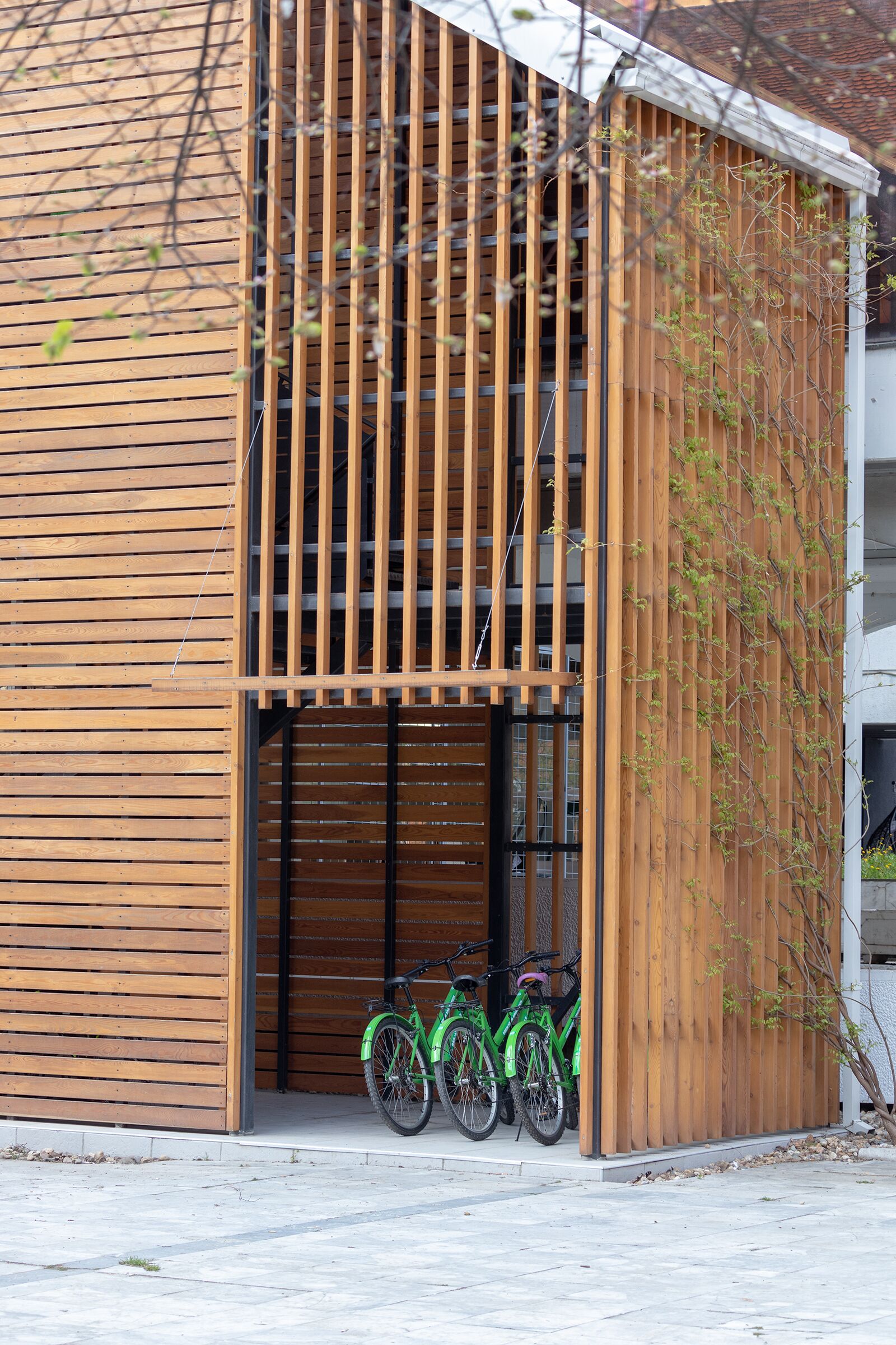 A modern building with a wooden facade, a covered entrance, and two bicycles parked outside.