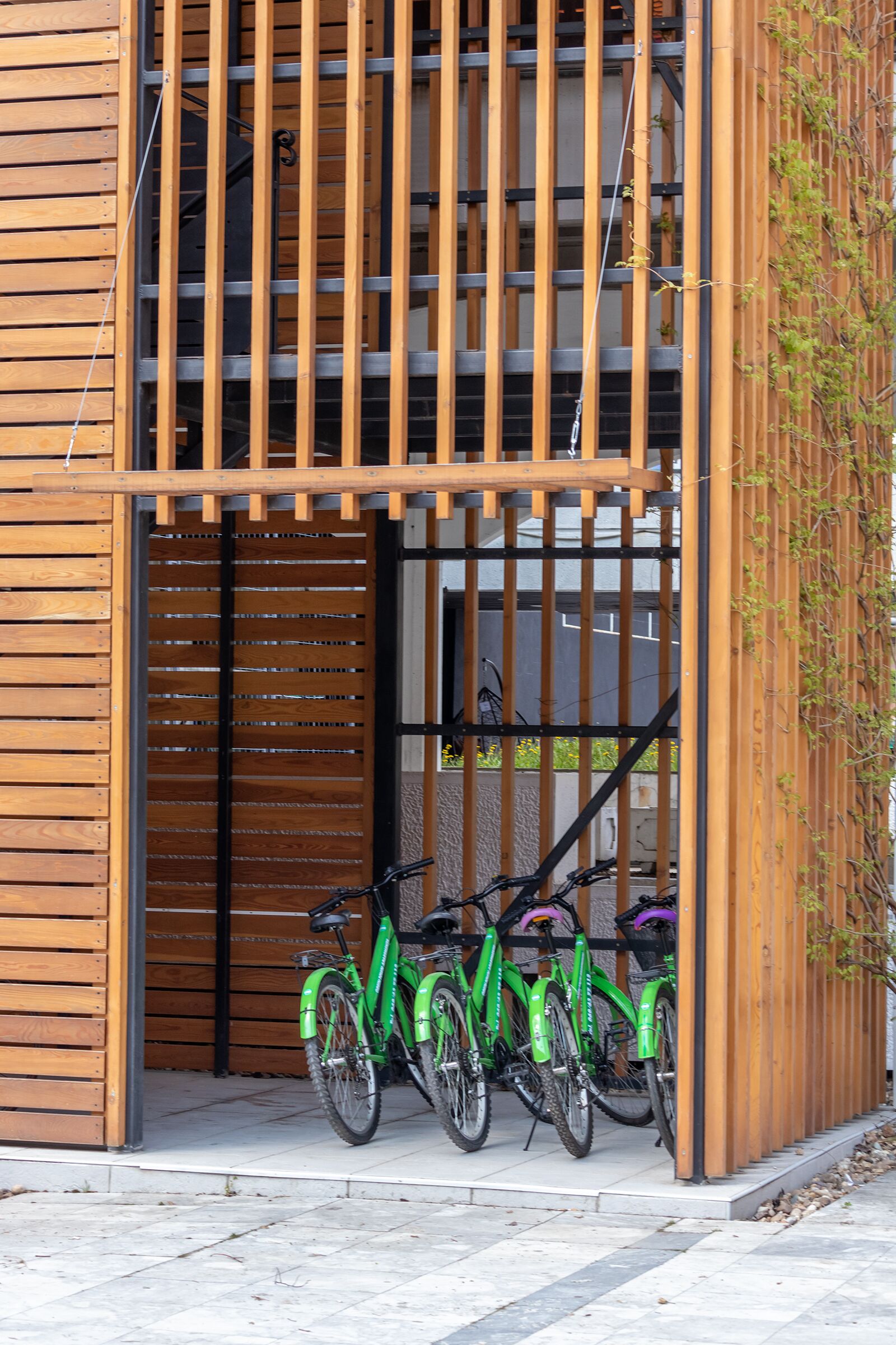 Un edificio moderno con facciata in legno, un cancello in metallo e due biciclette parcheggiate davanti.