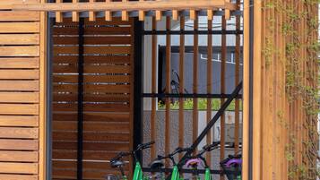 Un edificio moderno con facciata in legno, un cancello in metallo e due biciclette parcheggiate davanti.