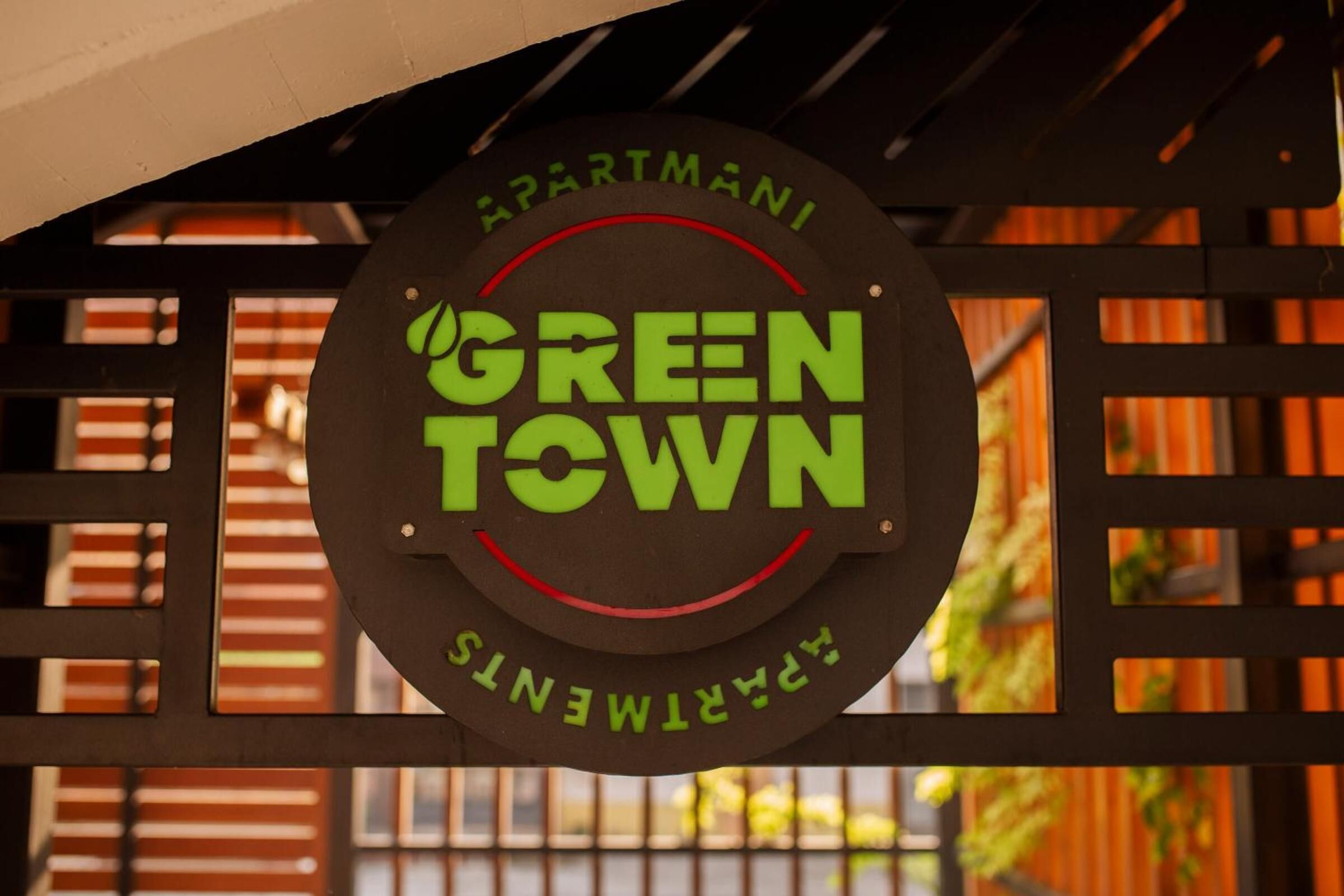 A circular sign with 'GREEN TOWN' and 'APARTMANS' text, mounted on a metal structure.