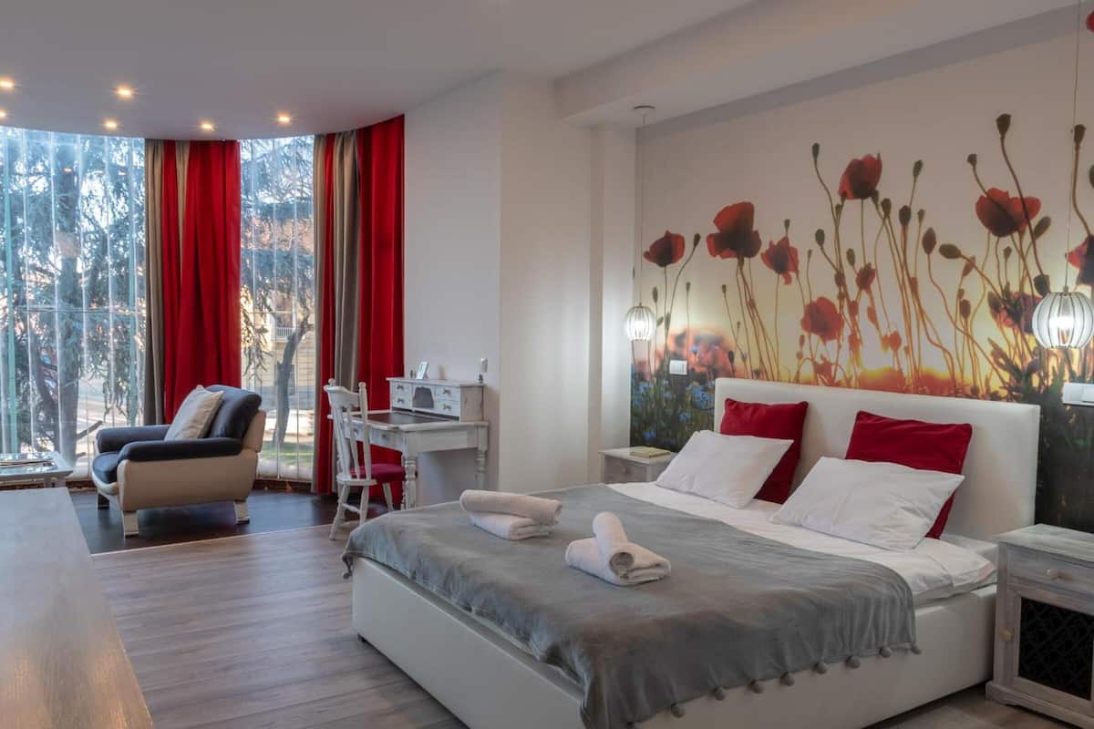 A modern hotel room with a large bed, a desk, and a chair.