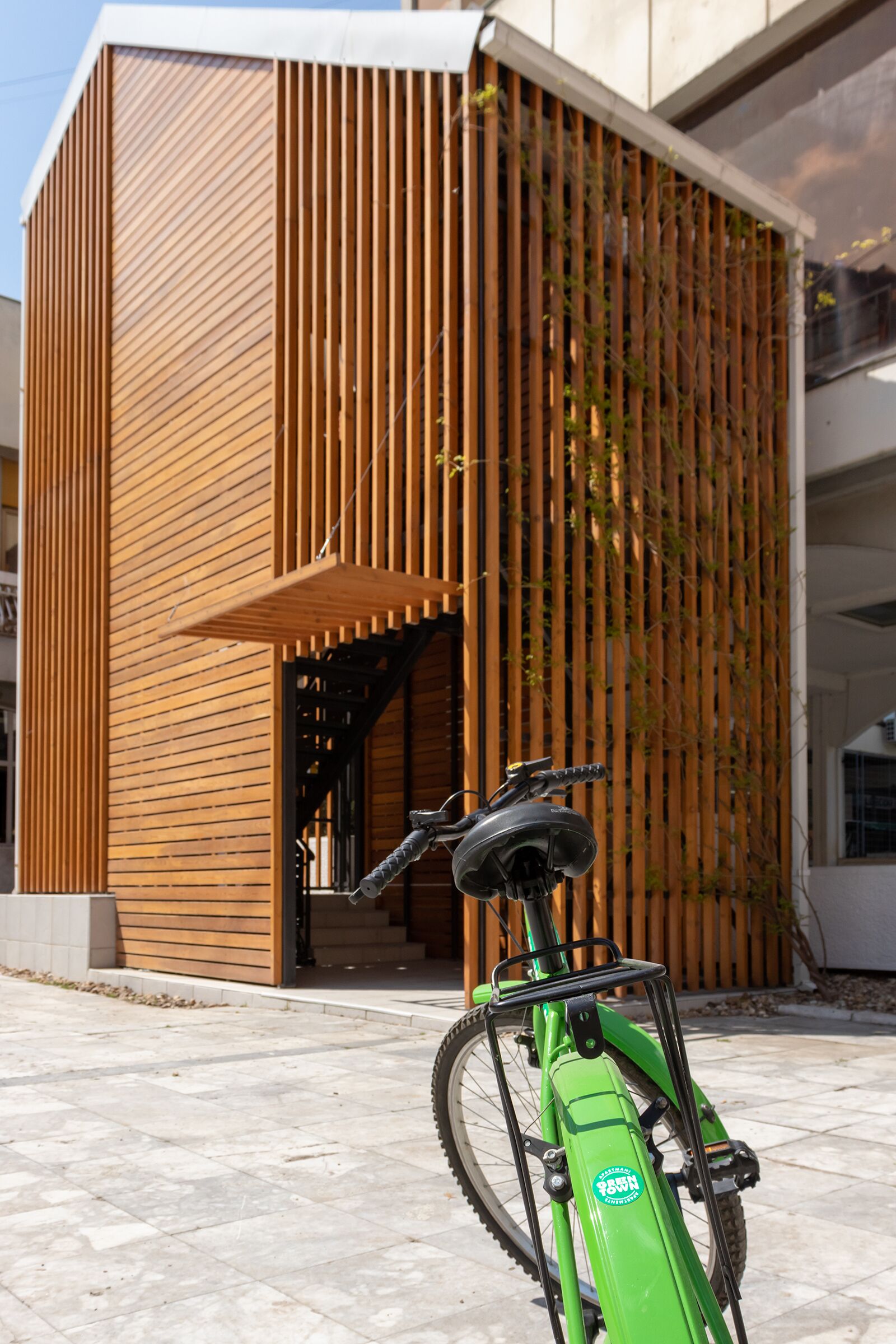 Un edificio moderno con fachada de madera y una bicicleta verde estacionada adelante.