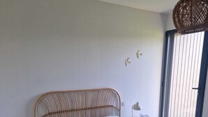 Un dormitorio con cama, dos mesitas de noche, una lámpara, una lámpara colgante y vistas a través de una ventana.