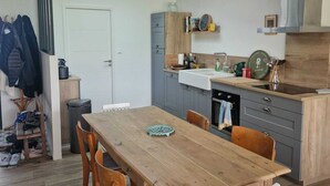 Una cocina moderna con una mesa de comedor, sillas y una lámpara colgante.