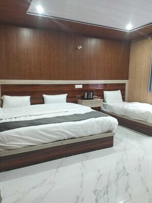 A hotel room with two beds, a wooden headboard, a marble floor, and a nightstand with a kettle. - Badri Kalash Valley (Badrinath)