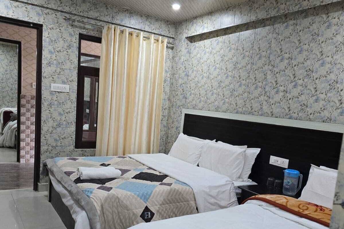 A hotel room with two beds, a bathroom, and a mirror.
