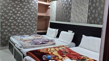 Habitación de hotel con dos camas, cabecero y papel tapiz estampado.