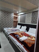 Habitación de hotel con dos camas, cabecero y papel tapiz estampado.