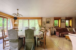 A dining area with a table, chairs, a chandelier, and a sofa. - Etretat sight Beach cliffs Golf - 332m2 13pers, 232m2 8pers, 107m2 5pers - 4str (Étretat)