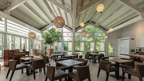 A spacious dining area with multiple tables and chairs, a piano, and large windows allowing natural light. - sun on the cloud (Shoufeng)