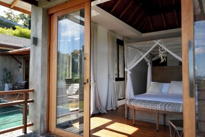 Une chambre à coucher avec un lit, une porte vitrée donnant sur l’extérieur et une vue sur le paysage.