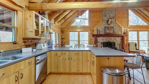 L’intérieur d’un chalet en bois comprend une cuisine, un coin repas et une cheminée.