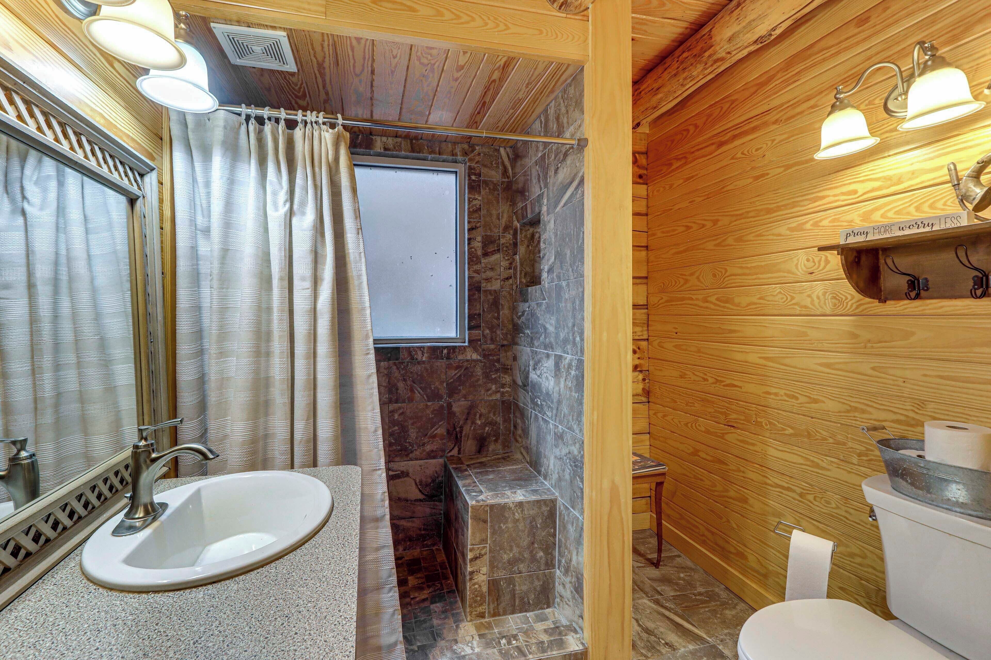 Een badkamer met een wastafel, spiegel, douche en toilet.