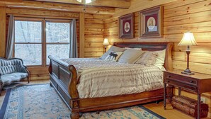 Une chambre dans une cabane en bois, avec un lit, deux lampes, une chaise et un ventilateur de plafond.