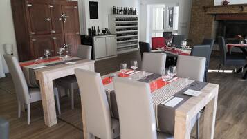 A dining area with wooden tables and chairs, a wine rack, and a fireplace.