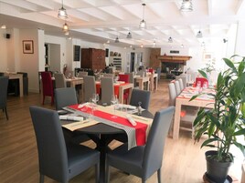 Un restaurante con varias mesas, sillas e iluminación colgante.