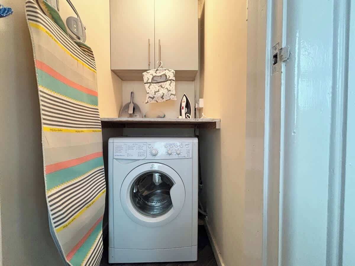 A compact laundry room with a front-loading washing machine, a striped towel, and a small cabinet above the machine.