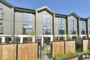 A modern apartment building with multiple units, each featuring balconies and large windows. - Spacious 2BR Townhouse with Yard Wilmer Street (Christchurch)