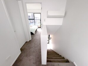 Eine Treppe führt zu einem Schlafzimmer mit einem Bett und Blick ins Freie.
