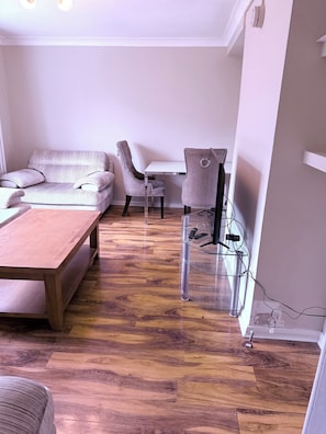 A modern living room with a sofa, a coffee table, and a TV stand with a glass shelf. - Beautiful 3-bedroom house in Glasgow perfect for your getaway (Glasgow)