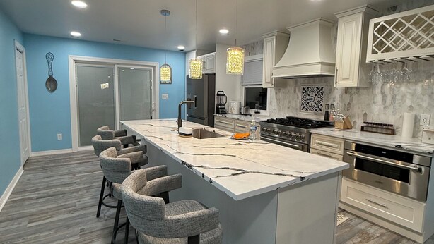 A modern kitchen with a central island, bar stools, stainless steel appliances, and a blue accent wall. - Indy Michigan rd house in northwest of Indianapolis near 465 north, 4brds 3 bath (Indianapolis)