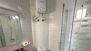 A bathroom with a glass shower enclosure, a sink with a marble countertop, a toilet, and a mirror above the sink.