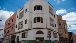 A multi-story building with a unique angular design, featuring a ground-level entrance and multiple windows.