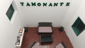 A hostel room with a bed, a small table, and a shelf with books and games.