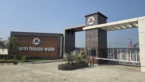 Una entrada con reja y un letrero que dice 'Farmhouse Wale' con un logotipo encima.