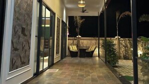 Un pasillo con un diseño moderno en el techo, una zona de estar con dos sillones y vistas al exterior.